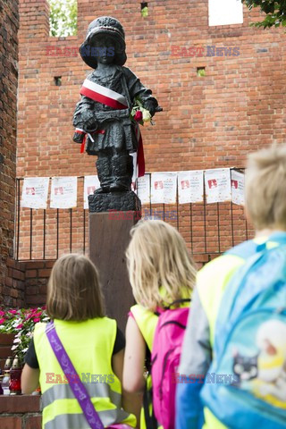 Dzieci i mlodzież oddają hołd pod pomnikiem Małego Powstańca