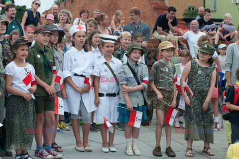 Dzieci i mlodzież oddają hołd pod pomnikiem Małego Powstańca