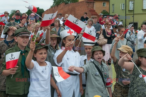 Dzieci i mlodzież oddają hołd pod pomnikiem Małego Powstańca