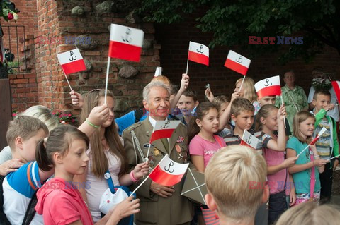 Dzieci i mlodzież oddają hołd pod pomnikiem Małego Powstańca