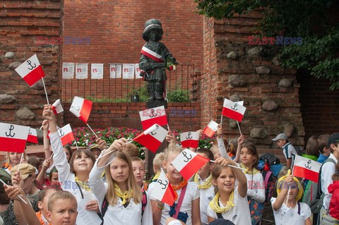 Dzieci i mlodzież oddają hołd pod pomnikiem Małego Powstańca