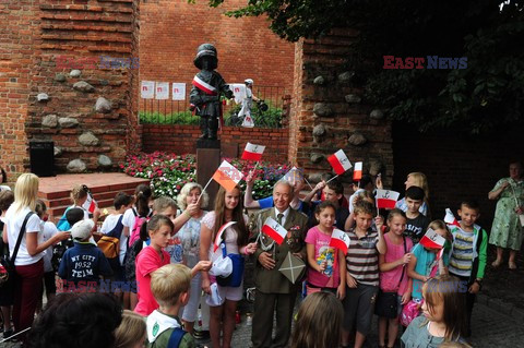 Dzieci i mlodzież oddają hołd pod pomnikiem Małego Powstańca