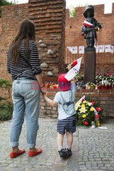 Dzieci i mlodzież oddają hołd pod pomnikiem Małego Powstańca