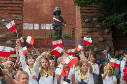 Dzieci i mlodzież oddają hołd pod pomnikiem Małego Powstańca