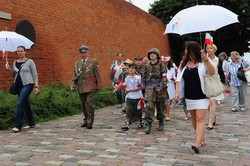 Dzieci i mlodzież oddają hołd pod pomnikiem Małego Powstańca